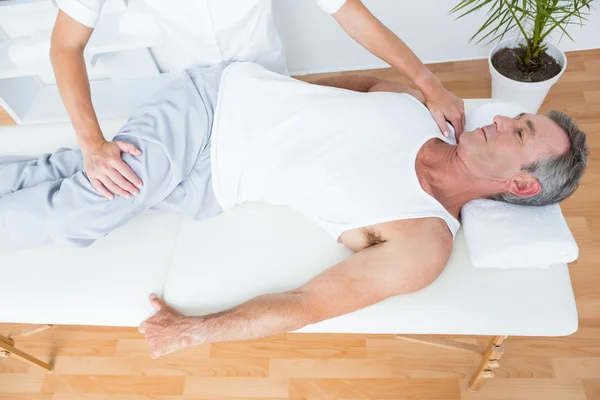 Fisioterapeuta fazendo massagem nas pernas para seu paciente — Fotografia de Stock