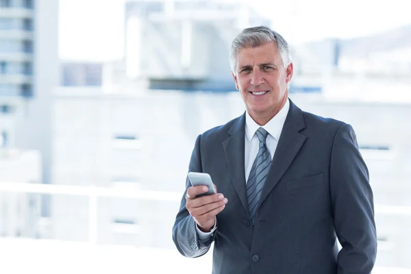 Biznesmen uśmiechający się przy użyciu swojego smartphone — Zdjęcie stockowe