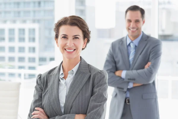 Smiling businesswoman looking at camera with colleague — Stock Photo, Image