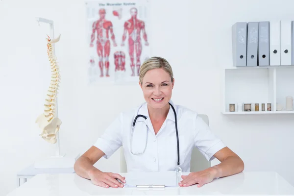 Doctor sitting at her desk smiling at camera — Stock Photo, Image
