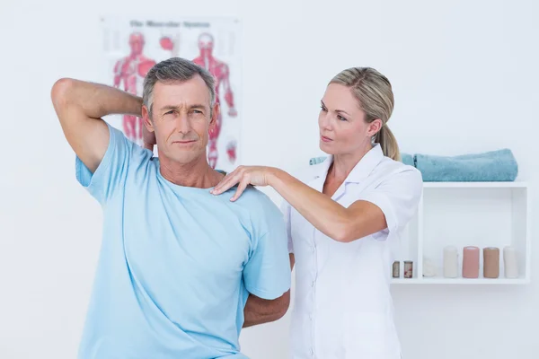 Médico esticando um braço de homem — Fotografia de Stock