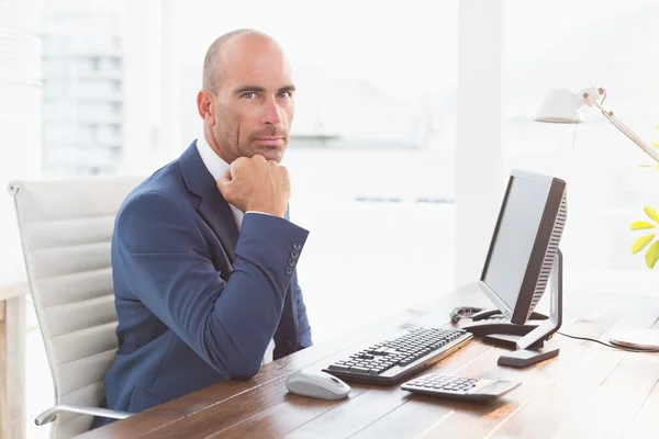 Businessman looking at camera at his desk — Stok fotoğraf