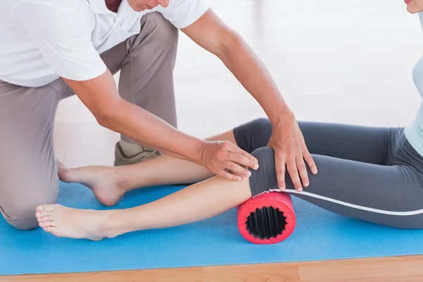 Entrenador trabajando con la mujer en la esterilla de ejercicio — Foto de Stock