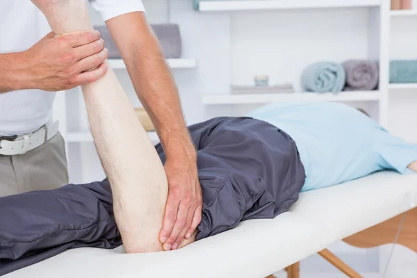 Fisioterapista che fa massaggi alle gambe al suo paziente — Foto Stock