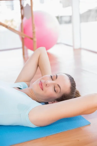 Smiling woman lying on exercise mat — Stock Photo, Image