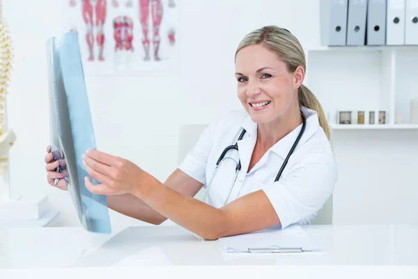 Médico sorridente olhando para a câmera e segurando raios-X — Fotografia de Stock