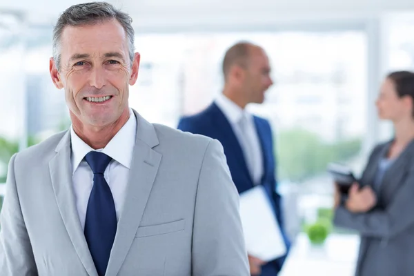 Homme d'affaires souriant avec un collègue derrière lui — Photo