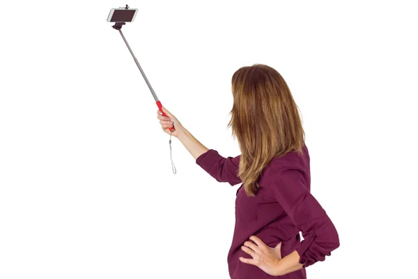 Wear view of pretty woman using a selfie stick — Stock Photo, Image