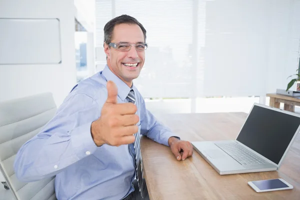 Geschäftsmann lächelt mit erhobenem Daumen in die Kamera — Stockfoto
