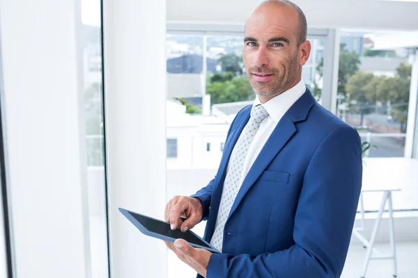 Businessman using a tablet and smiling at the camera — Stock Photo, Image
