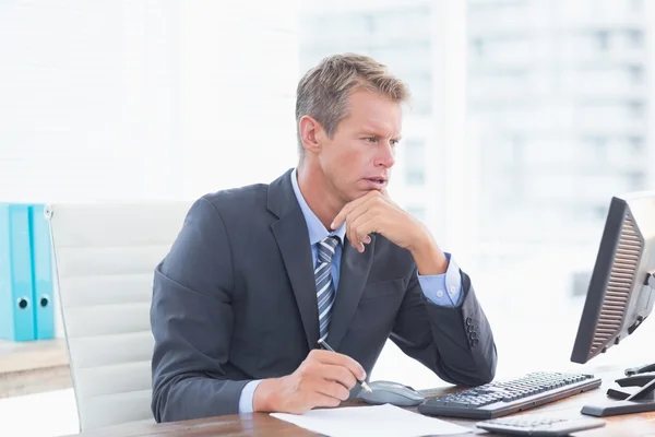 Serious businessman on his pc — Stockfoto