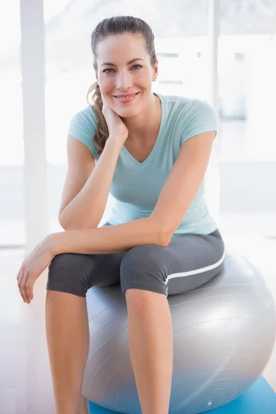 Femme regardant la caméra et assise sur le ballon d'exercice — Photo