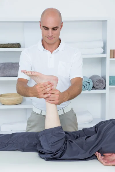 Fisioterapeuta haciendo masaje de piernas a su paciente — Foto de Stock