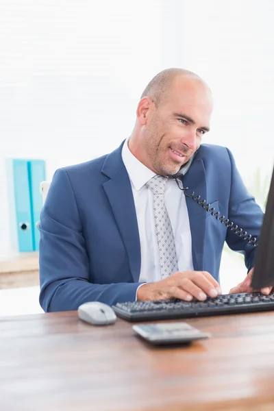 Businessman on the phone and using his computer — Stockfoto