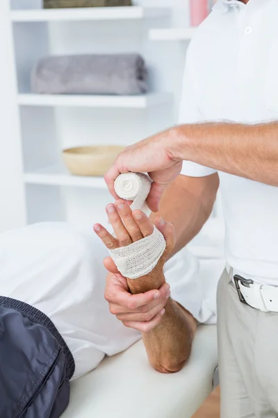 Doctor bandaging his patient hand — Stock Photo, Image