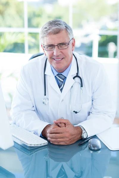 Médico sonriente sentado en su escritorio — Foto de Stock