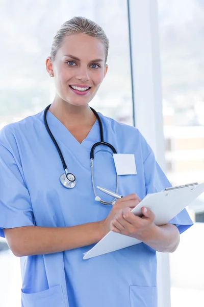 Feliz doctor escribiendo en el portapapeles — Foto de Stock