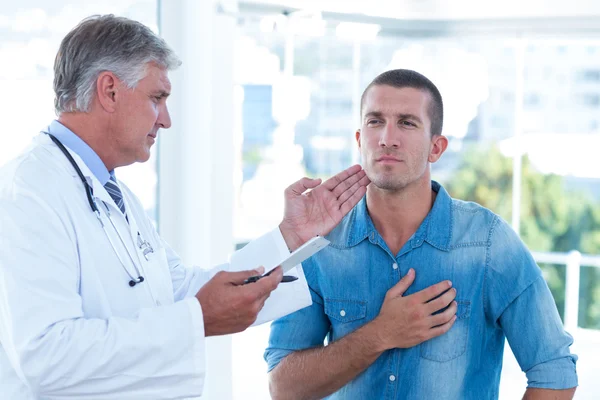 Doctor examinando el cuello de sus pacientes —  Fotos de Stock