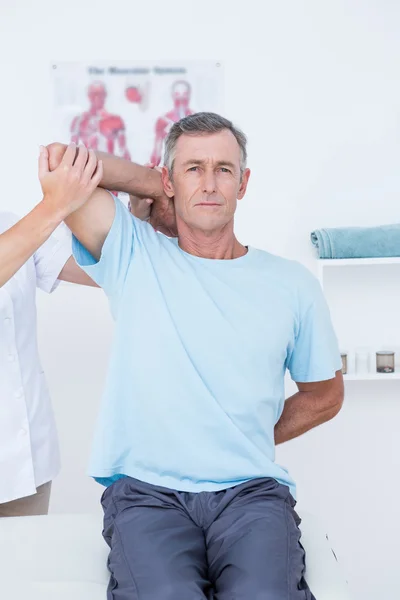 Médico esticando um braço de homem — Fotografia de Stock