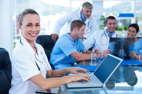 Bonito médico sorrindo digitando no teclado — Fotografia de Stock