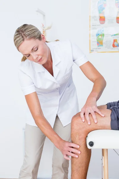 Doctor examining her patient knee — Stock Photo, Image