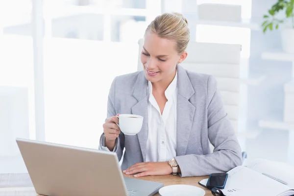 Affärskvinna dricka kaffe bakom hennes dator — Stockfoto