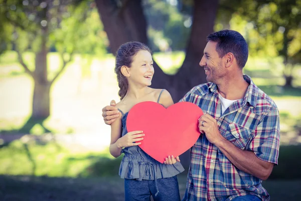 Vader en dochter houden een hart in het park — Stockfoto