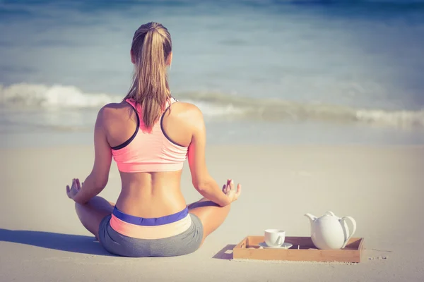 Fitte Frau beim Yoga am Strand — Stockfoto