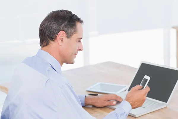 Geschäftsmann schickt einen Text am Schreibtisch — Stockfoto