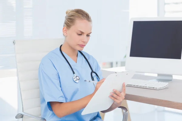 Enfermera concentrada escribiendo en portapapeles — Foto de Stock