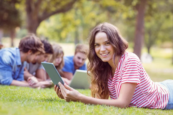 Ładna brunetka za pomocą tabletu w parku — Zdjęcie stockowe