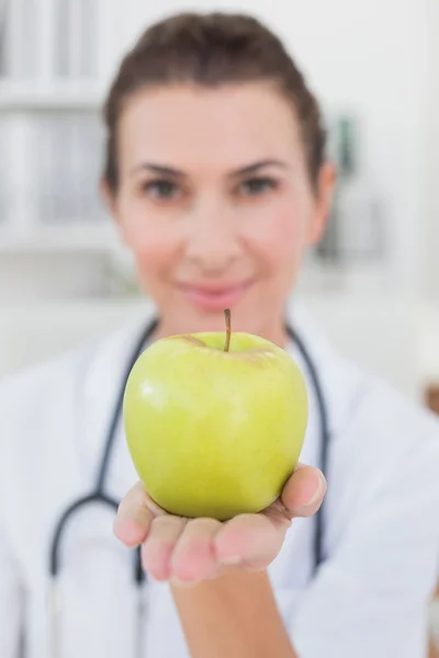 Usmívající se doktor ukazuje apple — Stock fotografie