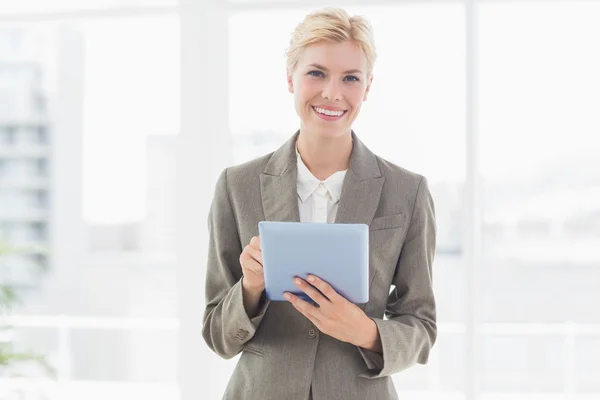 Smiling businesswoman looking at camera and using her tablet — Stok fotoğraf