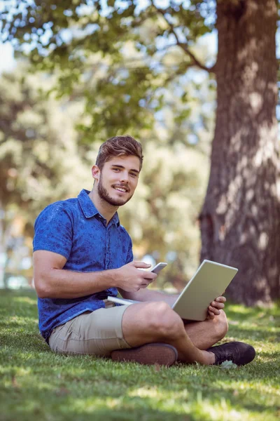 Hipster using laptop and phone in the park — Stok fotoğraf