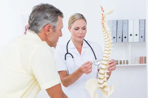 Médico mostrando a su paciente un modelo de columna vertebral — Foto de Stock