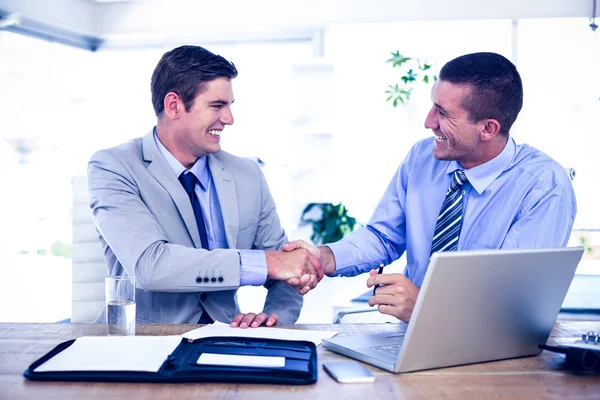 Businessmen shaking hands at desk — Stock Photo, Image