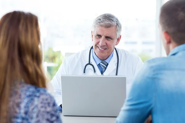 Sorridente medico parlando con coppia — Foto Stock