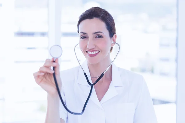 Leende läkare titta på kameran och visar stetoskop — Stockfoto