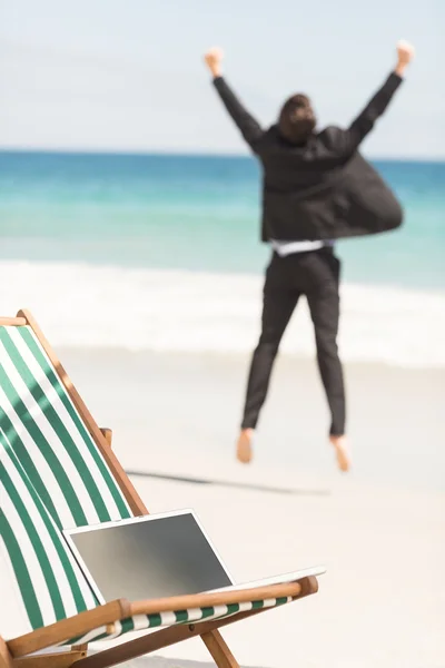 Happy businessman cheering at the beach — Stockfoto