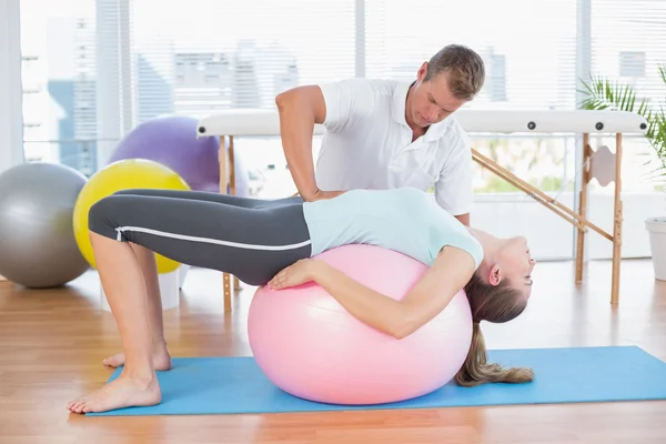 Trainer working with woman on exercise ball — Stock Photo, Image