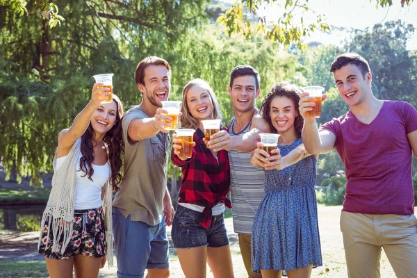 Счастливые друзья в парке пьют пиво — стоковое фото