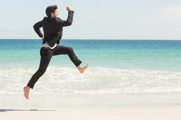 Businessman jumping in front of the sea — Stock Photo, Image