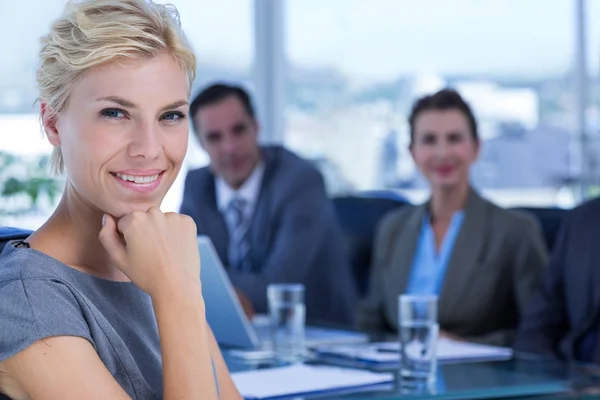 Businesswoman smiling at camera with colleagues behind — Stock Photo, Image