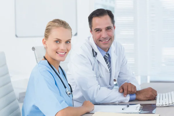 Médico sonriente y enfermera mirando a la cámara — Foto de Stock