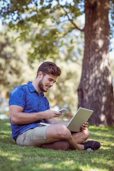Hipster using laptop and phone in the park — ストック写真