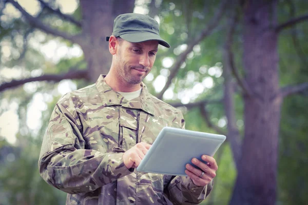 Солдат смотрит на планшетный компьютер в парке — стоковое фото