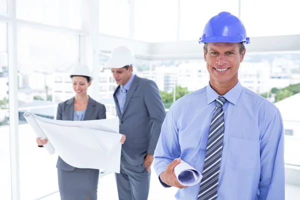 Businessmen and a woman with hard hats and holding blueprint — Stock Photo, Image