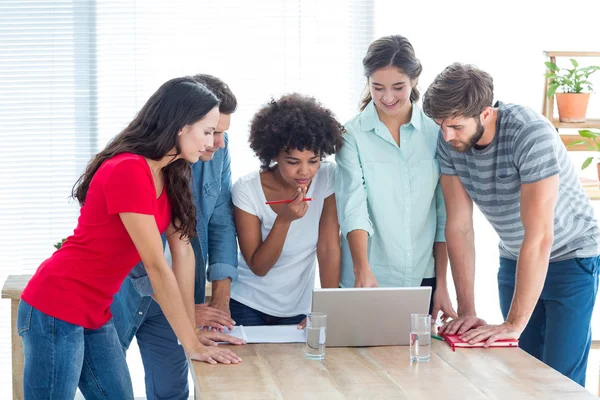 Colleagues gathered around a laptop at office — Stock Photo, Image