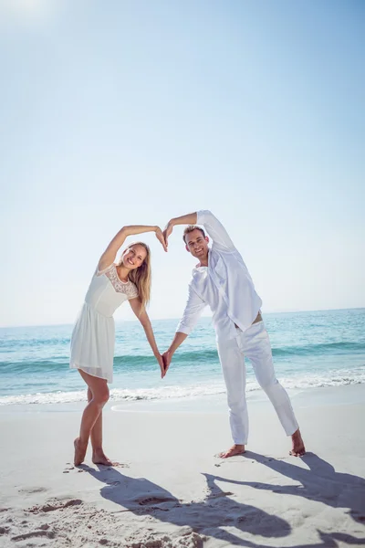 Happy couple forming heart shape with their hands — Stock Photo, Image