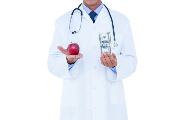 Doctor holding cash and red apple — Stok fotoğraf